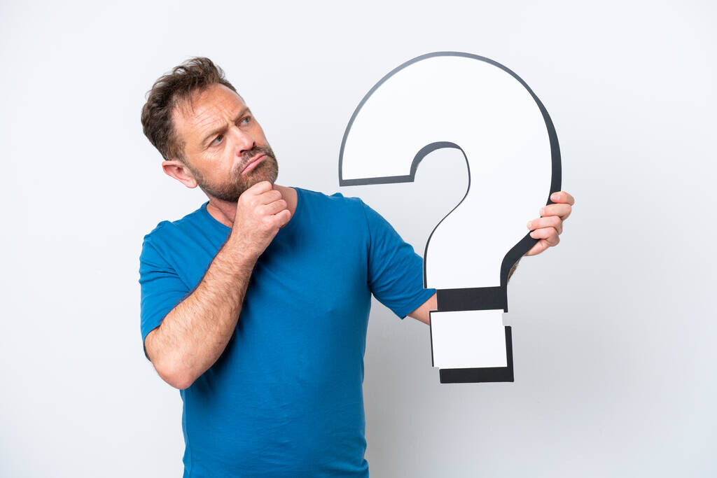 Middle age caucasian man isolated on white background holding a question mark icon and having doubts