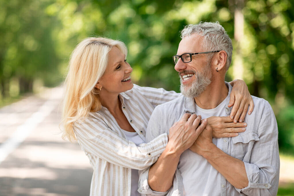 Happy romantic mature couple embracing while walking together in city park